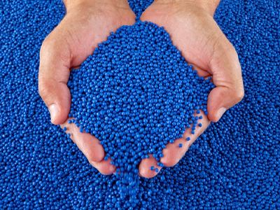 Hands holding blue plastic pellets